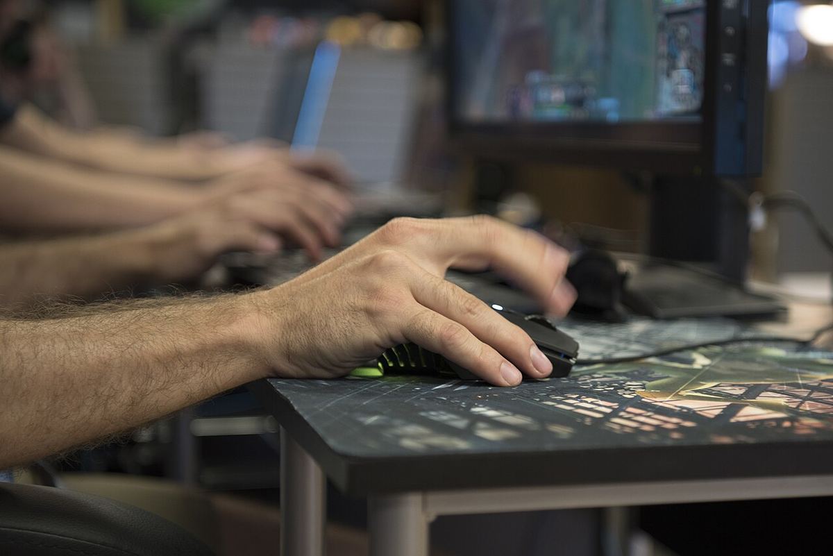 Ruka hráča na myši počas turnaja pred monitorom